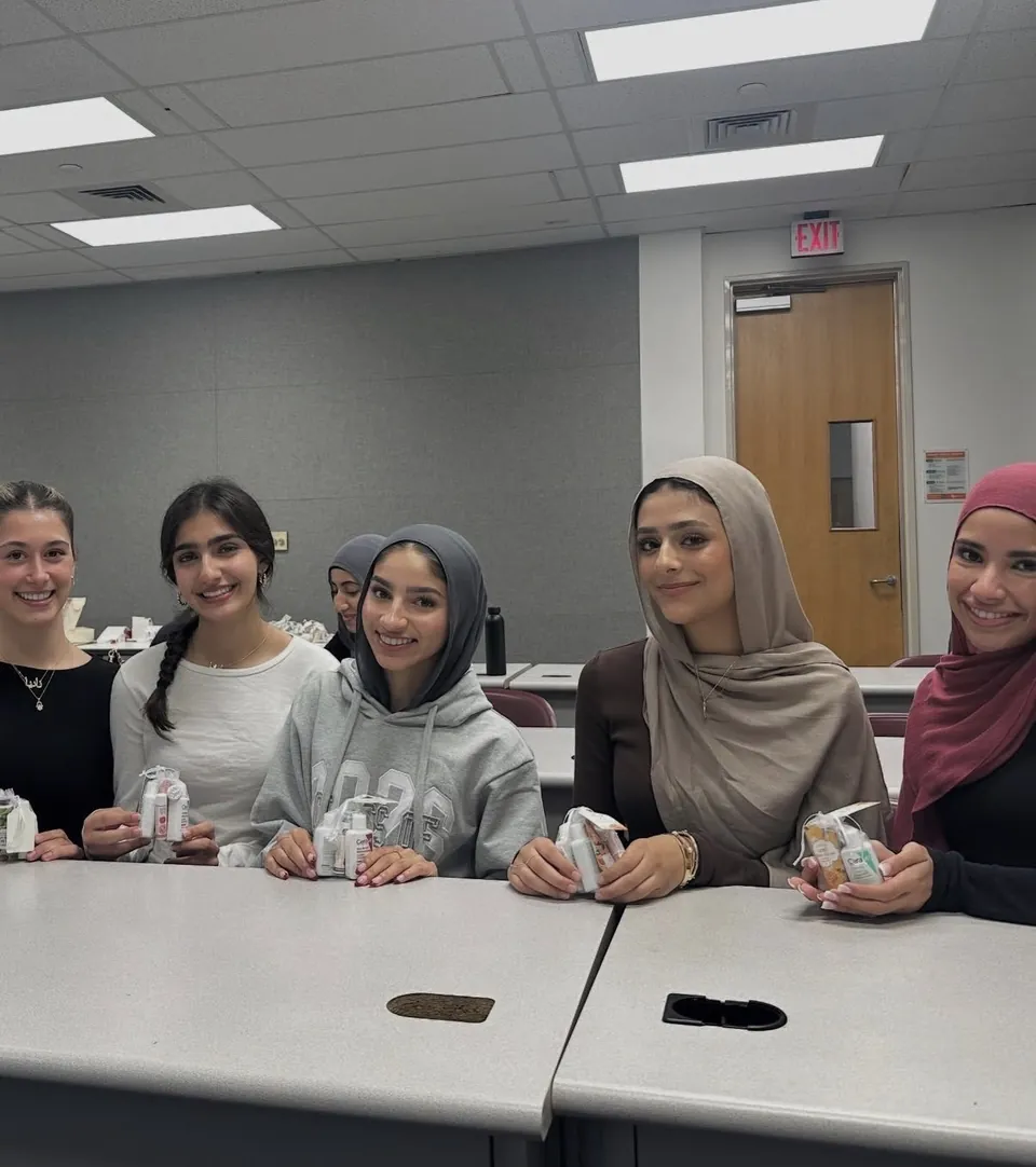 Five members smiling around a table, each holding a finished care kit.