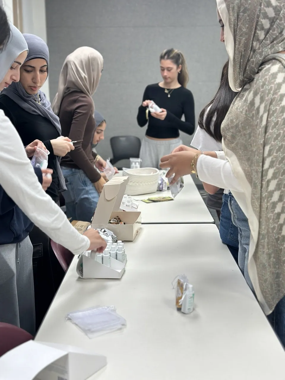 Members working on both sides of a long table, sorting supplies into care kits.