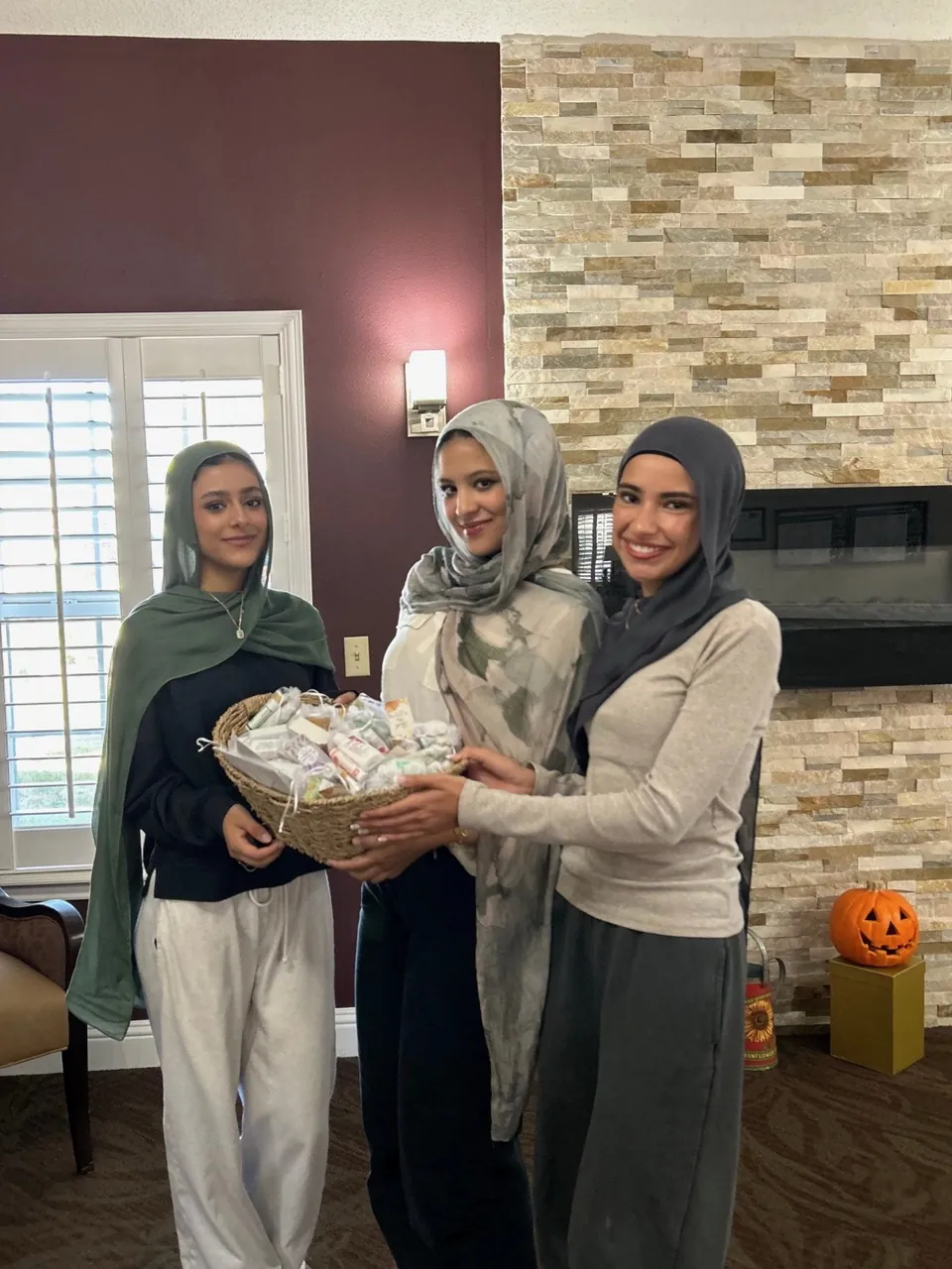 Three members at a nursing home holding a basket full of finished care kits.